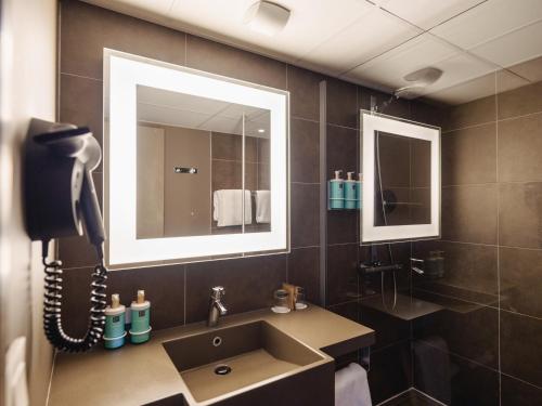 a bathroom with a sink and a phone at Novotel Nantes Centre Gare in Nantes