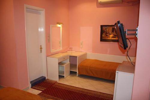a bathroom with a bed and a sink and a television at Hotel Avra in Kardítsa