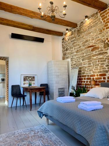 a bedroom with a brick wall and a bed and a table at Apartamenty Magdalena in Lublin
