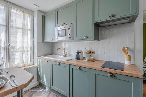 une cuisine avec des armoires bleues et un évier dans l'établissement Pluton, à Trouville-sur-Mer