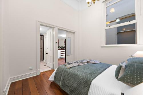 a white bedroom with a bed and a window at Ultimate Fremantle Location in Fremantle