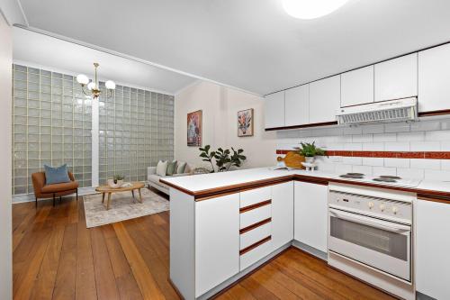 a kitchen with white cabinets and a living room at Ultimate Fremantle Location in Fremantle