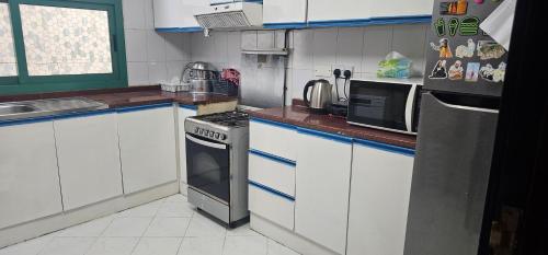 a kitchen with white cabinets and a stove top oven at UrduEnglishFamilyApartmen in Sharjah