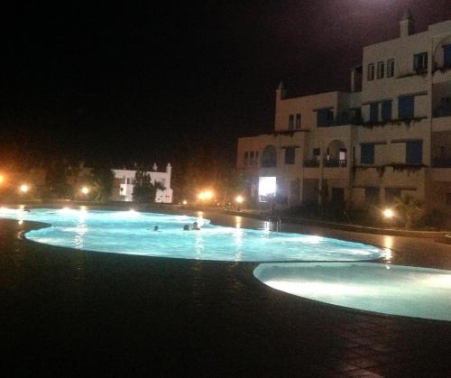 a pool at night with people swimming in it at Bel appartement, vue imprenable sur la mer, 80 m2, et super terrasse in Marina Smir