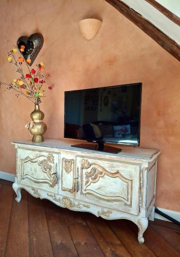 Un televisor encima de una mesa con un jarrón. en Apartment Noorderloft, en Hornhuizen