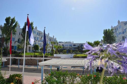 a bench in a park with flags and flowers at Bel appartement, vue imprenable sur la mer, 80 m2, et super terrasse in Marina Smir