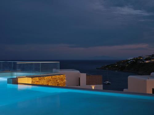 a swimming pool with a view of the ocean at night at Iria Blue Mykonos in Platis Yialos Mykonos