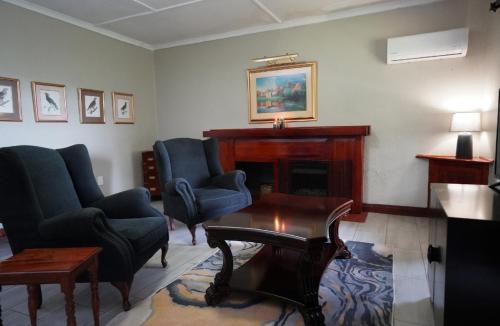 a living room with two chairs and a fireplace at Coach House Hotel & Spa Tzaneen in Tzaneen