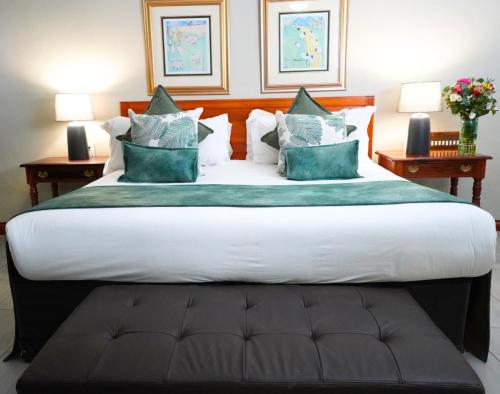 a large bed in a hotel room with two tables at Coach House Hotel & Spa Tzaneen in Tzaneen