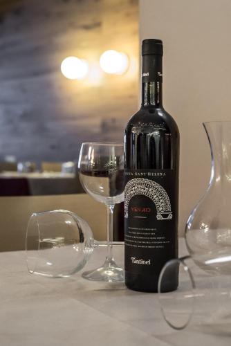 a bottle of wine sitting next to two glasses at Biker Hotel Al Gallo Forcello in Passo Pramollo