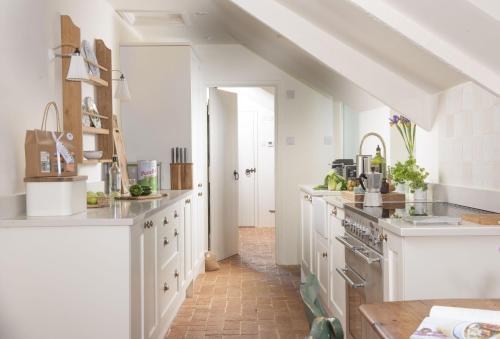 a large kitchen with white cabinets and a staircase at Besloe in Delabole