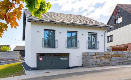 a white house with a green garage at Apartment 1 - Schmiedefeld - klein und fein in Schmiedefeld am Rennsteig