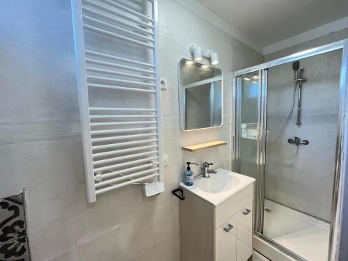 une salle de bain blanche avec une douche et un lavabo dans l'établissement Appartement Cosy 600m de la plage, à Fouesnant