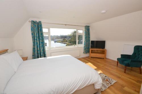 a bedroom with a bed and a window and a television at Coots - beautiful property in the heart of Wroxham sits on the waterside in Wroxham