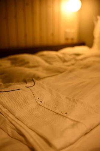 an unmade bed with a shirt on top of it at Hotel Unica in Biei