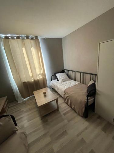 a bedroom with a bed and a coffee table at Studio spacieux in Creil
