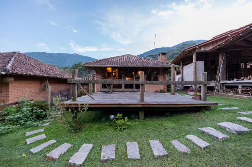 a house with a wooden deck in the yard at Estalagem Engenho de Serra - Parque Nacional do Itatiaia - Parte Alta in Itamonte