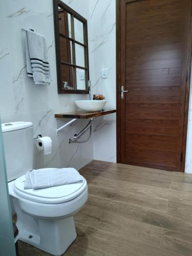a bathroom with a white toilet and a sink at Refúgio da Família Koch - casa de campo in Sinimbu