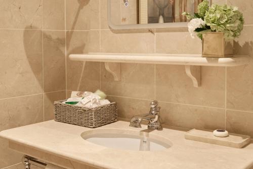 a bathroom sink with a basket and a mirror at The Montague On The Gardens in London