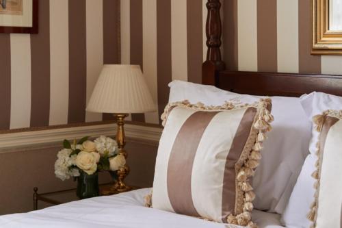 a bed with a pillow and a lamp and a vase of flowers at The Montague On The Gardens in London