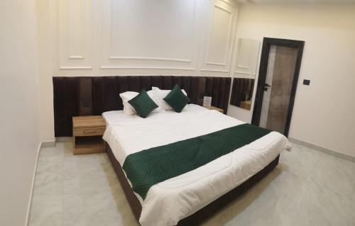 a bedroom with a large bed with green pillows at Hotel The Coal in Alīgarh