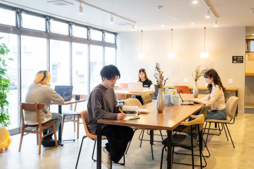 a group of people sitting at tables with laptops at Grand Hostel LDK Odori Park in Sapporo