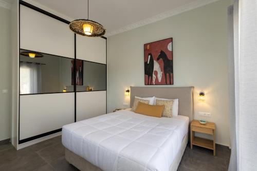 a bedroom with a large white bed and a mirror at Elia Syros in Vari