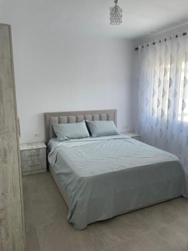 a white bedroom with a large bed and a window at S&S City Apartment in Shkodër