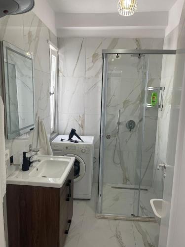 a bathroom with a shower and a sink and a washing machine at S&S City Apartment in Shkodër