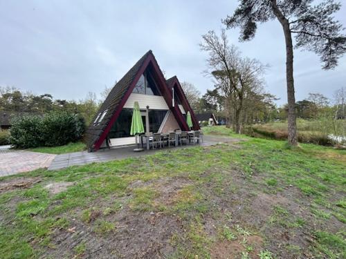 a small house with a table and chairs in front of it at Duo family bungalow Vosvilla Limburg in Stramproy