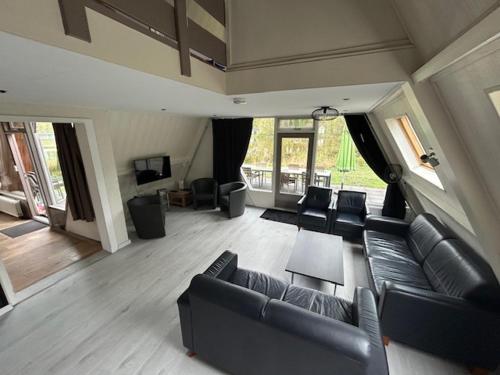 a living room with black couches and a television at Duo family bungalow Vosvilla Limburg in Stramproy