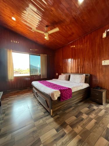 a bedroom with a large bed in a wooden room at Daksh The Valley Resort - Saputara in Saputara