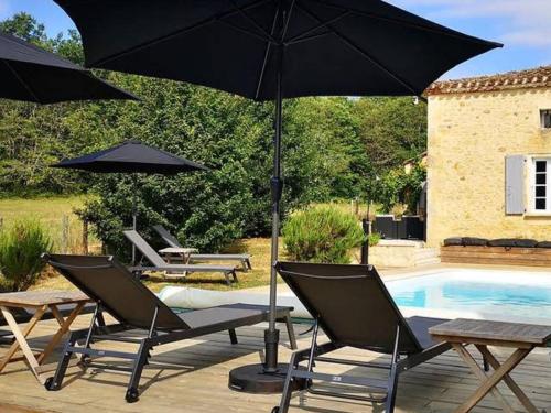- un groupe de chaises et un parasol à côté de la piscine dans l'établissement L' Ecurie, à Lavaur
