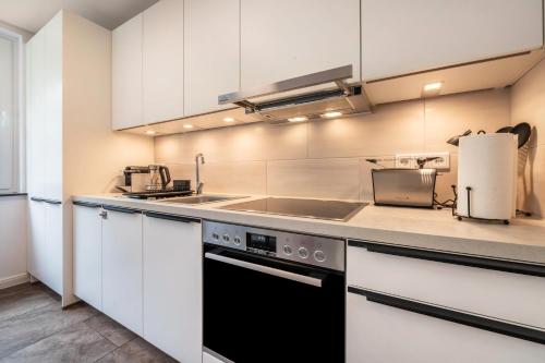 a kitchen with white cabinets and a sink and a stove at Kleines Glück in Delmenhorst