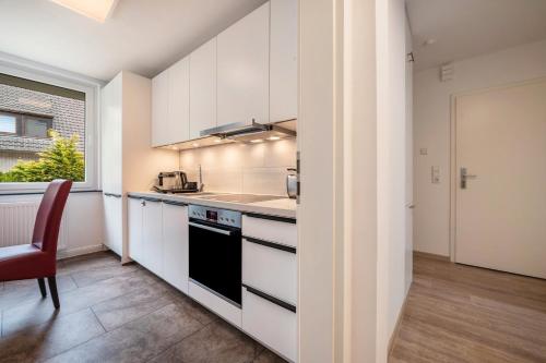 a kitchen with white cabinets and a red chair at Kleines Glück in Delmenhorst