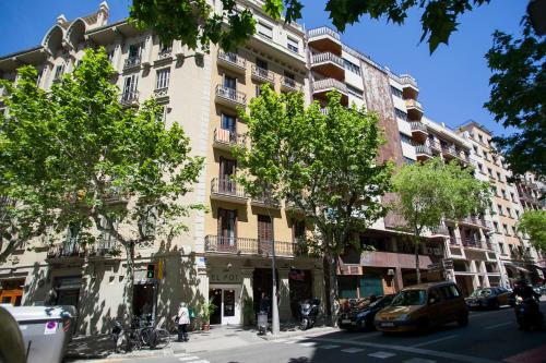 un gran edificio blanco en una calle de la ciudad con árboles en BBarcelona Còrsega Flats, en Barcelona