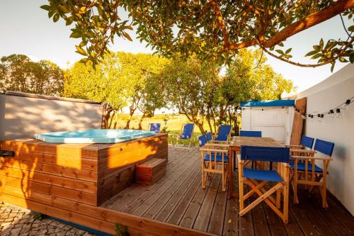 a deck with a hot tub and tables and chairs at The Indigo Windmill Retreat, Peniche in Atouguia da Baleia