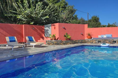 a swimming pool with two chairs and a fence at Villa Margarita Galini in Skopelos Town