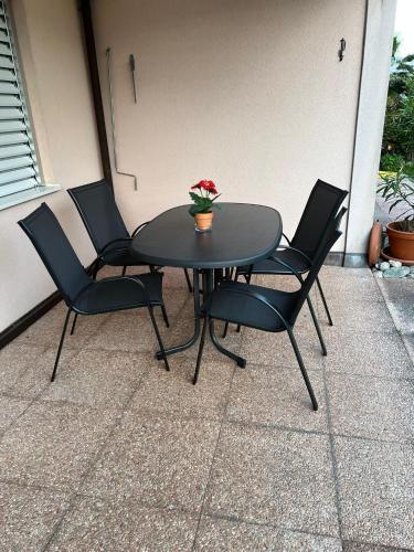 a black table with four chairs and a plant on it at Ascona Principessa Apt 3 in Ascona