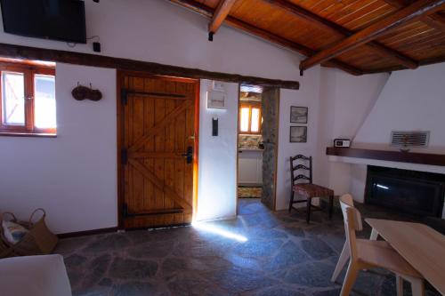 a room with a wooden door and a table and chairs at Fteri Stone House in Platanos, Akrata in Plátanos