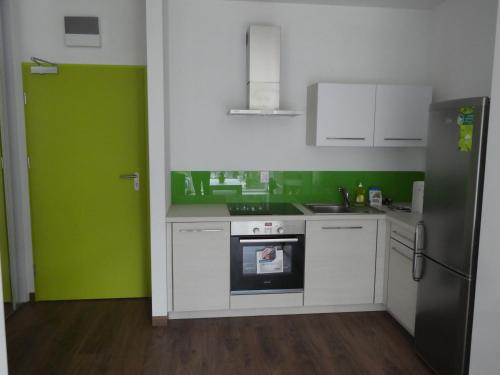 a kitchen with green walls and white cabinets and an oven at Cube Apartamenty in Lublin