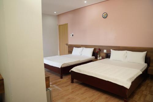 a room with two beds and a clock on the wall at KHÁCH SẠN ĐẾ VƯƠNG in Cao Lãnh