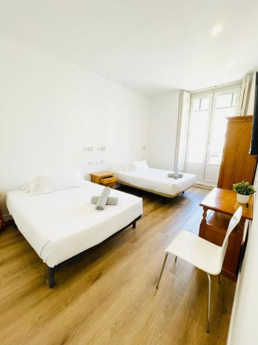a room with two beds and a table and a chair at Hostal Ruano in Madrid