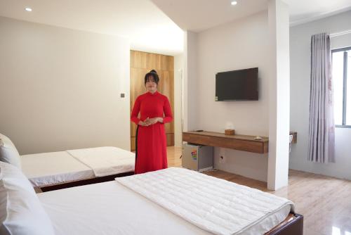 a woman in a red dress standing in a hotel room at KHÁCH SẠN ĐẾ VƯƠNG in Cao Lãnh