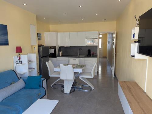 un salon avec un canapé bleu et une cuisine dans l'établissement Ti Caraïbe appartement vue mer et parking gratuit du 1 juin au 30 septembre, à Canet