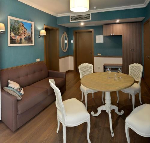 a living room with a couch and a table and chairs at ZENTRUM Hotel in Chişinău