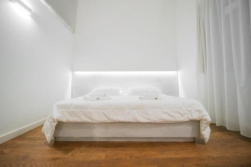 a white bed in a white room with a window at Sui Tetti Luxury Rooms in Lecce