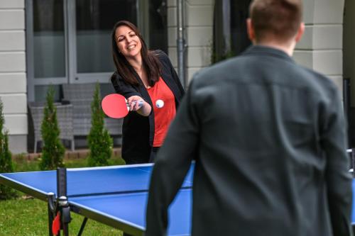 a woman playing ping pong on a ping pong table at Weinberghotel Edelacker in Freyburg