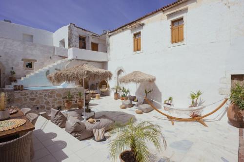 a white building with a patio with plants and umbrellas at Casa Moro in Episkopi 16km from Rethymno in episkopi-chania