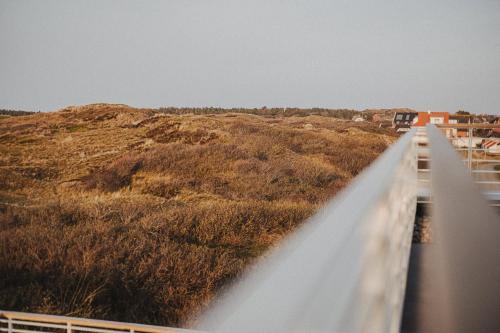 a bridge over a grassy field with a building at Silt & Sand Langeoog in Langeoog